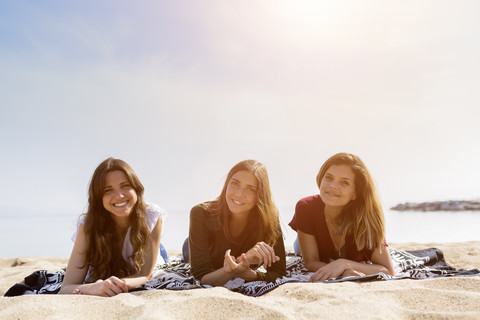 Portrait of three female friends relaxing on the beach stock photo