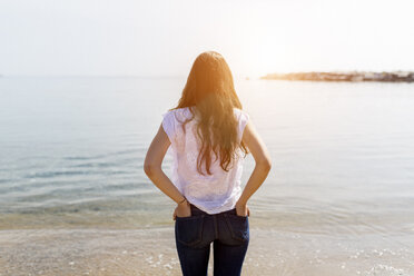 Rear view of young woman standing at the sea - GIOF03031