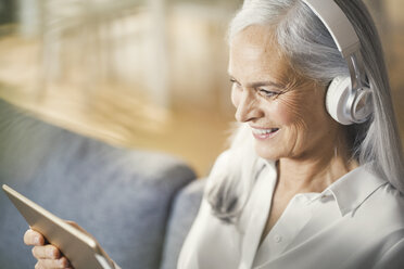 ältere Frau mit digitalem Tablet und Kopfhörern - SBOF00477