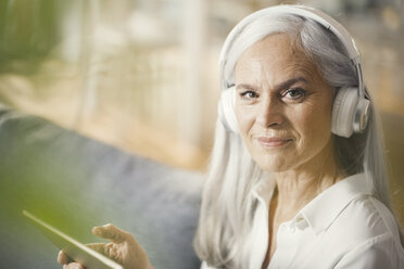 ältere Frau mit digitalem Tablet und Kopfhörern - SBOF00478