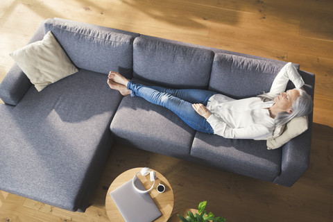 Ältere Frau entspannt auf Couch, lizenzfreies Stockfoto