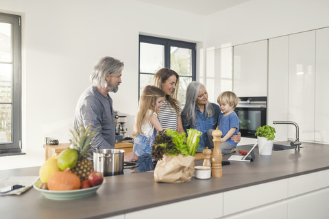 Grandparents with grandchildren and their mother standing in kitchen stock photo