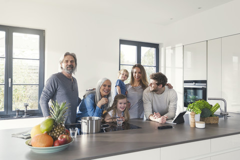 Happy family with grandparents and children standing in the kitchen stock photo