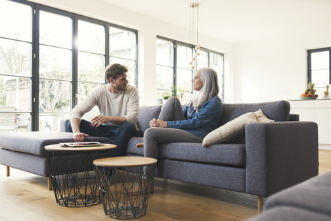 Sohn sitzt auf der Couch und spricht mit seiner Mutter, lizenzfreies Stockfoto