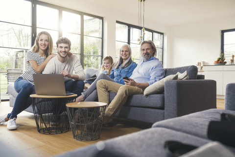 Extended family sitting on couch, using mobile devices stock photo