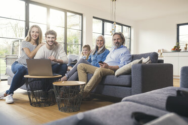 Extended family sitting on couch, using mobile devices - SBOF00523
