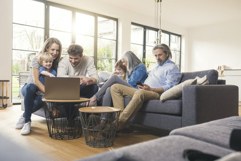 Großfamilie sitzt auf der Couch und benutzt mobile Geräte, lizenzfreies Stockfoto