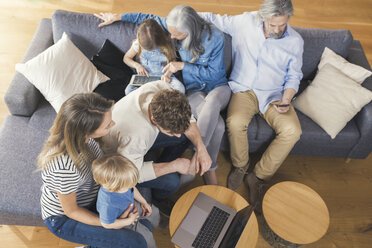 Großfamilie sitzt auf der Couch und benutzt mobile Geräte - SBOF00525