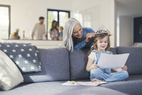 Grandmother playing with granddaughter, puuting crown on her head stock photo