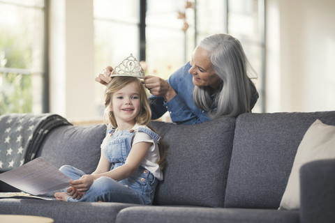 Großmutter spielt mit Enkelin, setzt ihr eine Krone auf den Kopf, lizenzfreies Stockfoto