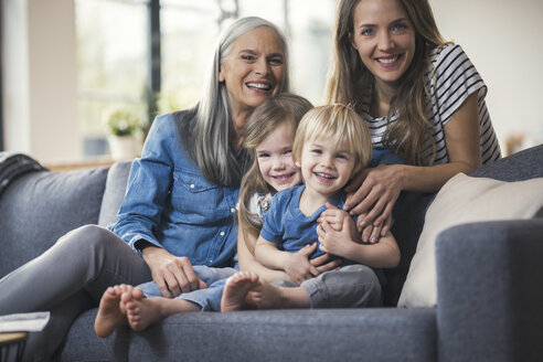 Großmutter und Mutter sitzen mit Kindern auf der Couch - SBOF00545