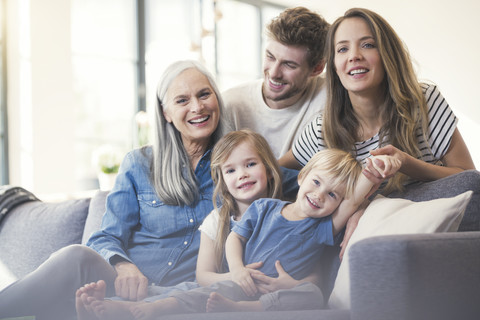 Extended family sitting on couch, smiling happily stock photo