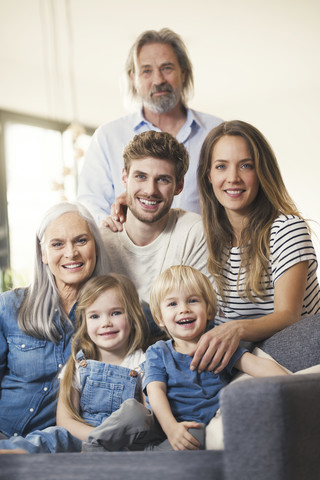 Großfamilie sitzt glücklich lächelnd auf der Couch, lizenzfreies Stockfoto