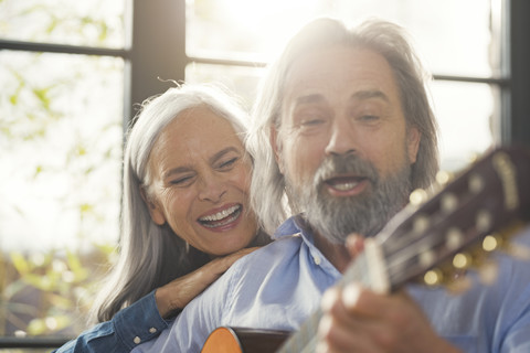Senior playing guitar and singing loud for his wife stock photo