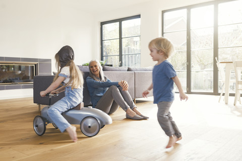 Großeltern beobachten die Großmutter beim Spielen im Wohnzimmer, lizenzfreies Stockfoto