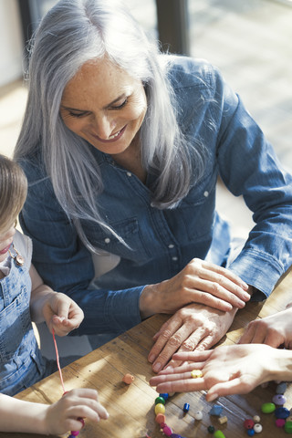 Großmutter, Enkelin und Mutter beim Auffädeln von Perlen, lizenzfreies Stockfoto