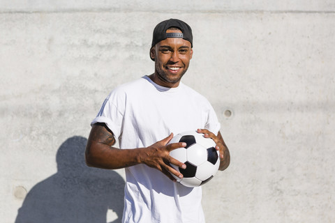 Portrait of smiling young man with soccer ball stock photo