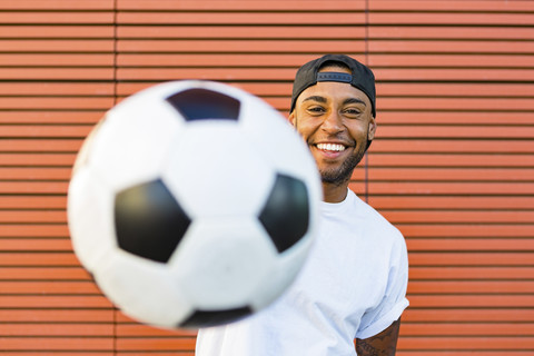 Porträt eines lachenden Mannes, der Spaß mit einem Fußball hat, lizenzfreies Stockfoto