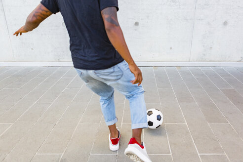 Rückenansicht eines jungen Mannes, der mit einem Fußball gegen eine Betonwand spielt, Teilansicht - MGIF00089