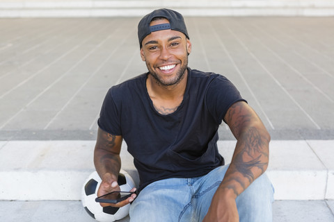 Portrait of laughing young man with smartphone stock photo