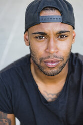 Portrait of serious young man with stubble wearing basecap - MGIF00093
