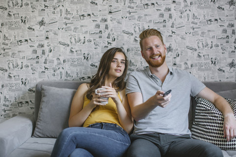 Ehepaar sitzt auf der Couch und sieht fern, lizenzfreies Stockfoto