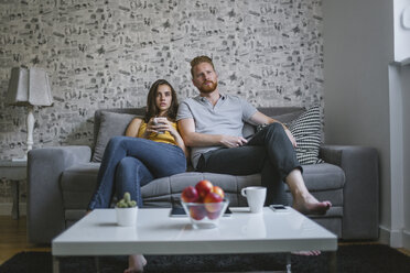Young couple sitting on couch watching TV - MOMF00210