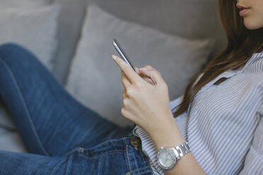 Woman on couch in the living room using cell phone - MOMF00217