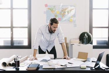 Architekt betrachtet den Bauplan in seinem Büro - GIOF03036