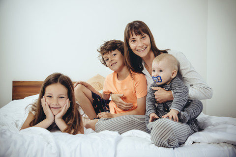 Happy mother in bed with her three children stock photo