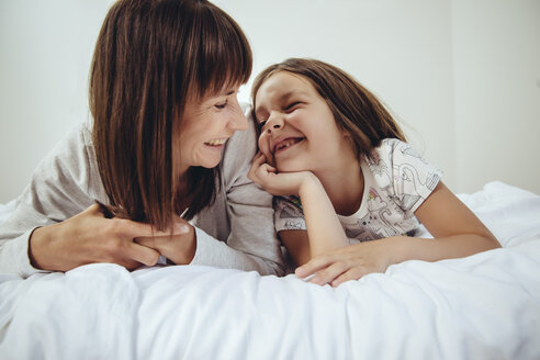 Glückliche Mutter und Tochter im Bett liegend - MFF03714