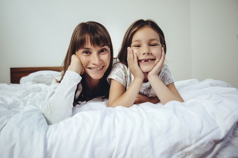 Porträt von glücklicher Mutter und Tochter im Bett, lizenzfreies Stockfoto
