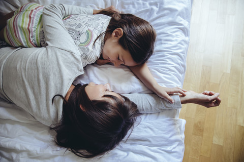 Mutter und Tochter kuscheln auf dem Bett, lizenzfreies Stockfoto