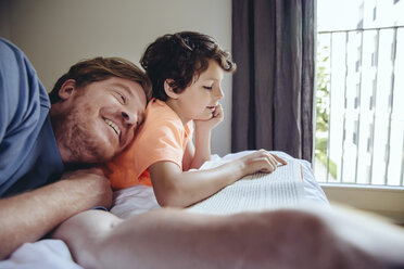 Son reading to his father on bed - MFF03726