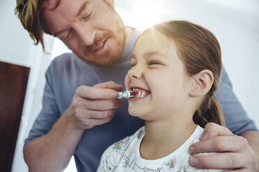 Father brushing daughter’s teeth in bathroom - MFF03734