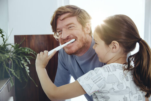 Daughter brushing her father’s teeth in bathroom - MFF03735