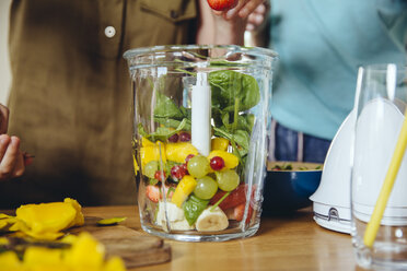 Nahaufnahme von Mutter und Kindern, die Obst in einen Smoothie-Mixer geben - MFF03754