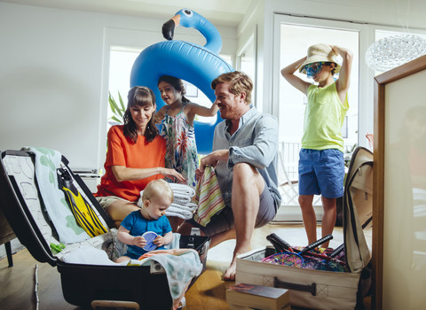 Glückliche fünfköpfige Familie beim Packen für die Urlaubsreise, lizenzfreies Stockfoto