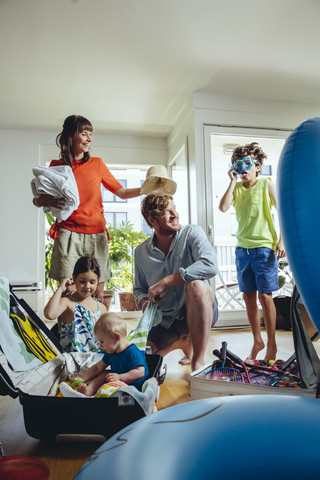 Glückliche fünfköpfige Familie beim Packen für die Urlaubsreise, lizenzfreies Stockfoto