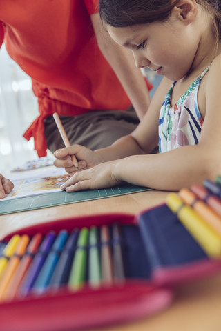 Mutter hilft Mädchen bei ihren Schularbeiten zu Hause, lizenzfreies Stockfoto