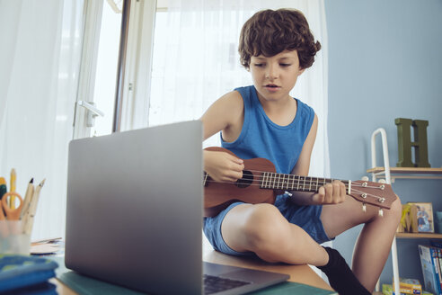 Junge spielt mit Laptop ein Lied auf einer Ukulele - MFF03792