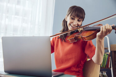 Frau benutzt Laptop, um ein Lied auf einer Geige zu spielen - MFF03793