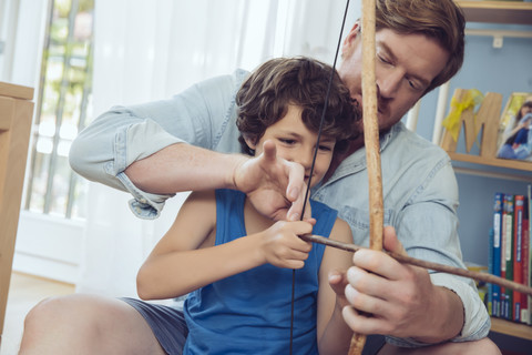 Vater zeigt seinem Sohn, wie man einen selbstgebauten Pfeil und Bogen benutzt, lizenzfreies Stockfoto