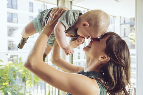 Mutter hebt ihr Baby zu Hause hoch, lizenzfreies Stockfoto