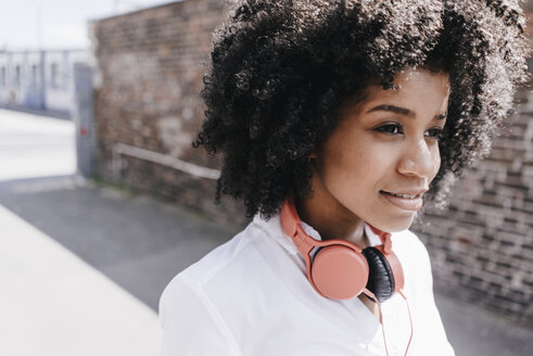 Junge Frau trägt Kopfhörer im Freien - KNSF02248