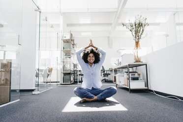 Glückliche junge Frau beim Yoga im Büro - KNSF02253