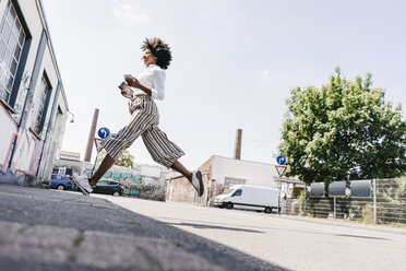 Vital young woman crossing the street - KNSF02254