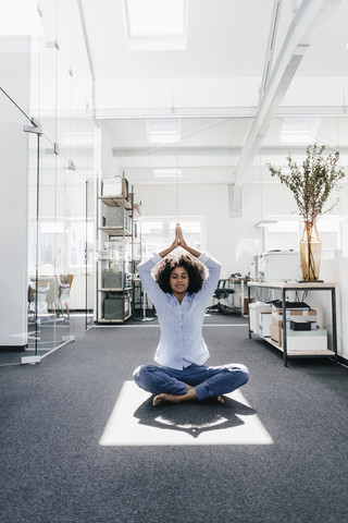 Young woman doing yoga in office stock photo