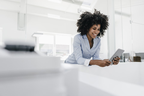 Smiling young woman using tablet in office stock photo