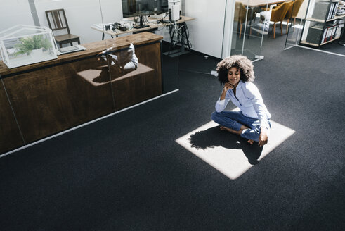 Young woman sitting on floor in office - KNSF02278